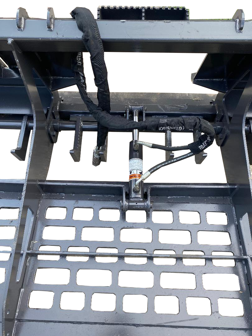 A close-up of the Skid Steer Land Leveler showcases intricate details such as metal grating, hydraulic cylinders, and black hoses, assembled meticulously on a concrete surface. The setup appears primed for attachment to a skid steer or land leveler, ensuring efficient groundwork.